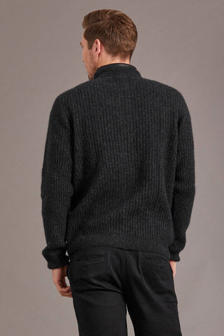 Man wearing a charcoal grey knitted jacket against a plain background