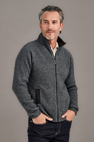 Man wearing a gray zip-up sweater against a plain background
