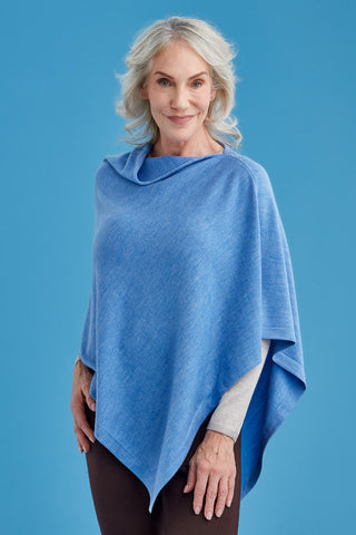 Woman wearing a blue poncho against a blue background