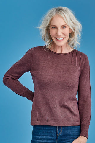 Woman wearing a mauve sweater against a blue background