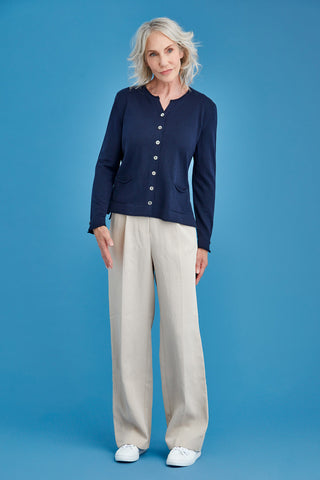 Woman wearing a navy cardigan and beige pants against a blue background