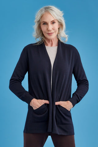 Woman wearing a navy long merino cardigan against a blue background