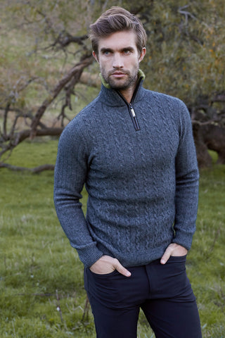 A man wearing a pewter grey cable knit jersey with contrast trim standing outdoors.